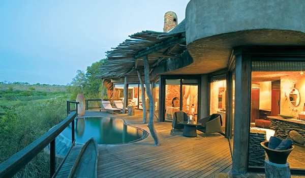 Imagem de um lodge da África com varanda ampla e piscina, em meio à natureza, ideal para experiências de hospedagem exclusivas.