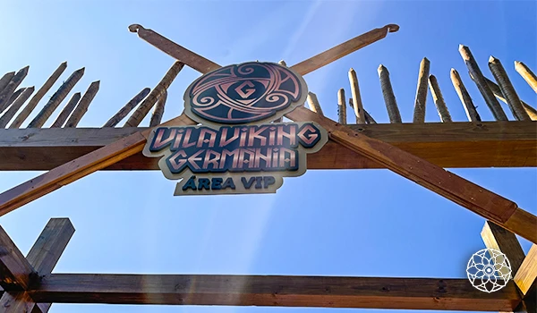 Entrada para o evento Dilaking Germain com decoração rústica, estrutura de madeira e sinalização personalizada em um dia de céu claro, ideal para amantes de games e tecnologia.