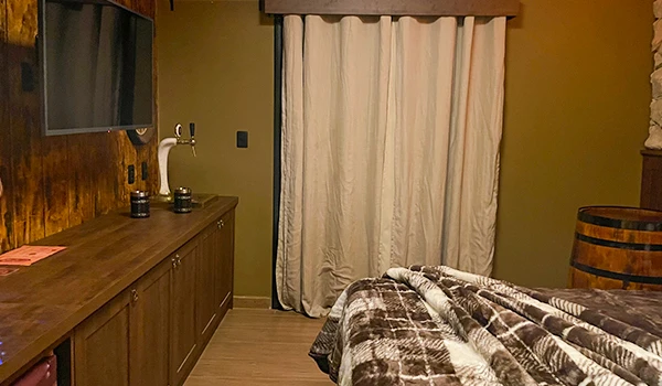 Quarto aconchegante com decoração rústica, cortinas de tecido leve, armário de madeira escura e uma parede de madeira no ambiente, ideal para relaxar.
