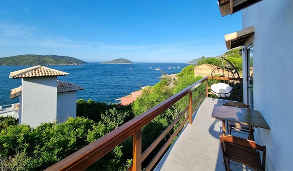 Vista do mar e ilha ao horizonte vista de varanda de hotel ou residência, com paisagem marítima, céu claro e vegetação exuberante ao redor. Hotéis para Lua de Mel no estado do Rio de Janeiro.