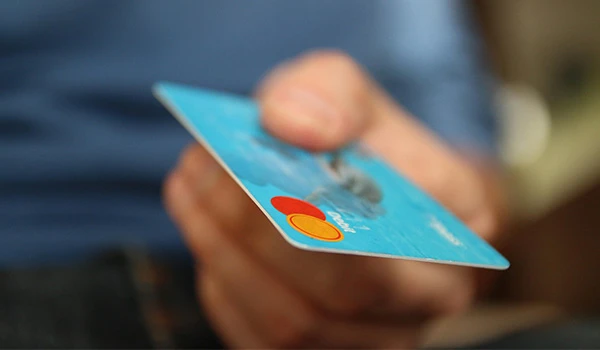 Pessoa segurando um cartão de crédito bancário com fundo desfocado, simbolizando transações financeiras e segurança financeira.