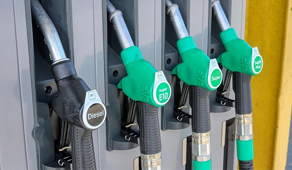 Mangueiras de postos de gasolina com diferentes tipos de combustível, incluindo diesel e gasolina, alinhadas em um suporte na bomba de combustível.