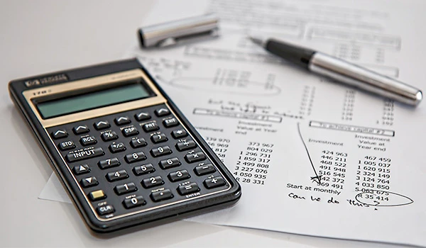Calculadora financeira e documentos com análise de dados e gráficos, ferramenta essencial para cálculos financeiros e administração de investimentos.