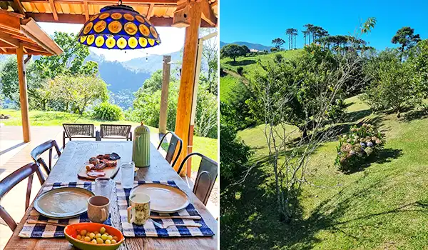 Imagem de um cenário ao ar livre com varanda, mesa de jantar com comida, cadeiras, iluminação colorida e uma paisagem verde com árvores e montanhas ao fundo, perfeito para relaxar e apreciar a natureza.