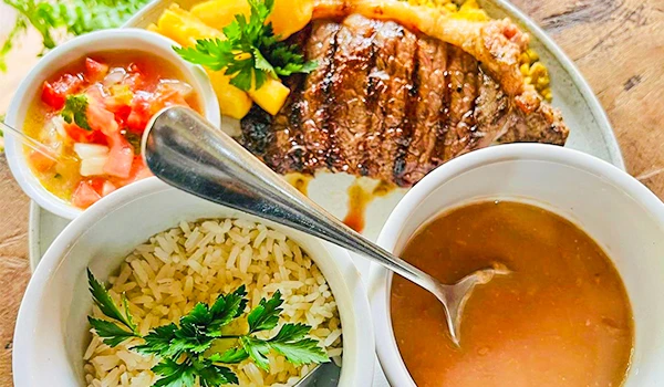 Imagem de um prato de comida com carne grelhada, arroz, feijão, salada e molho, ideal para quem busca receitas de carne ou comida caseira brasileira.