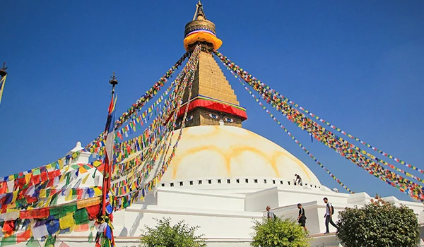 Imagem da Estupa de Boudhanath decorada com bandeiras de oração coloridas, simbolizando espiritualidade e cultura budista no Nepal.