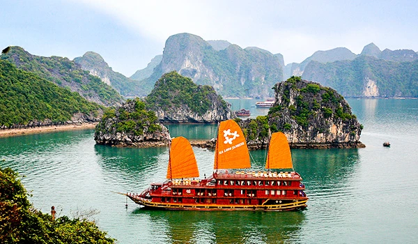 Imagem de uma tradicional embarcação de turismo em Ha Long Bay, na Vietnã, rodeada por ilhas de rochas calcárias e águas verdes na Ásia.