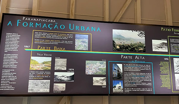 Painel informativo sobre a formação urbana de Paranuapabiaca, destacando as partes baixa e alta, com fotos e textos históricos.