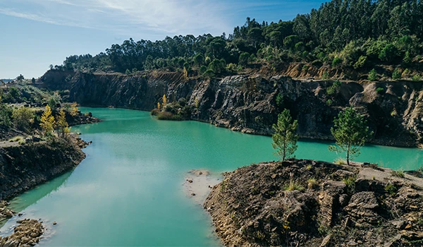 Paisagem de um rio de água clara e calma cercado por penhascos e vegetação verde em uma área natural, ideal para turismo de aventura e ecoturismo.