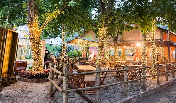 Terrasse ao ar livre decorada com luzes de Natal e iluminação aconchegante, ideal para relaxar e desfrutar de momentos agradáveis com amigos ou família.