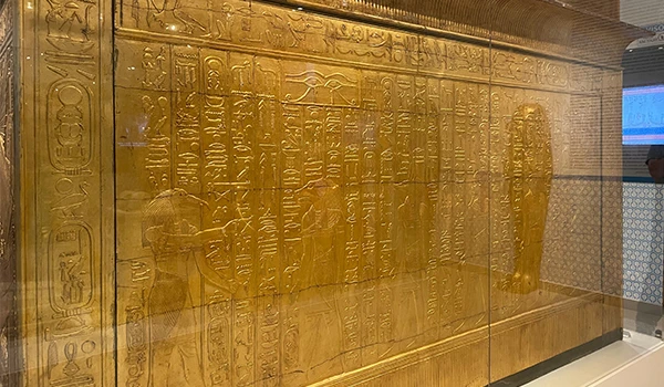 Painel decorativo de parede com hieróglifos egípcios em relevo dourado, representando a antiga cultura do Egito, perfeito para decorar ambientes temáticos ou históricos.