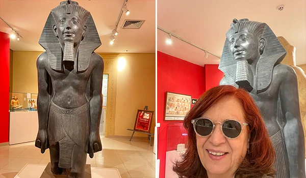 Imagem de uma réplica de uma escultura de Tutancâmon, o famoso faraó egípcio, exibida em um museu. A escultura é de tamanho grande, de cor escura, com detalhes históricos, ao lado Deusa Rodrigues. Museu Egípcio e Rosacruz em Curitiba.