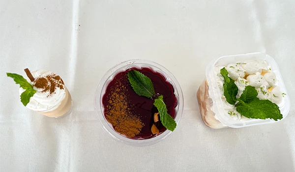 Sobremesas variadas com chantili, geleia e creme, decoradas com hortelã em uma superfície branca