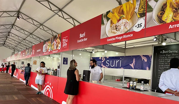 Perú Mucho Gusto pratos típicos, evento com clientes e atendentes ao longo do espaço, destacando o nome 'Suri' na fachada.