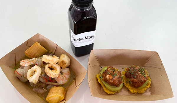 Imagem de pratos de comida com frutos do mar, como lula e camarão, acompanhados de molho em um recipiente de papel. Perú Mucho Gusto pratos típicos