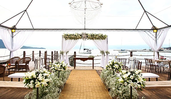 Espanha. Cenário ideal para eventos ao ar livre com decoração elegante em branco, vista para o mar, cadeiras organizadas e iluminação natural em uma tenda de festa.