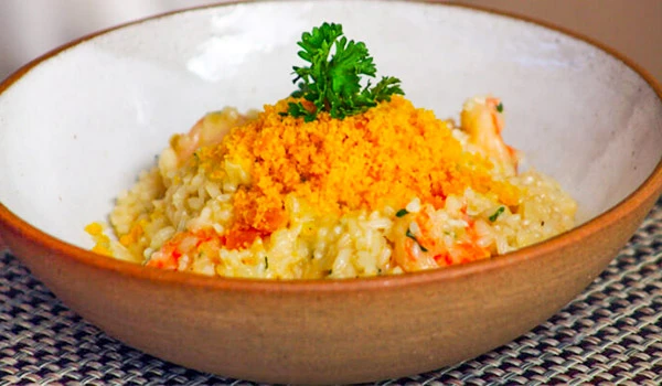 Prato de risoto de frango com queijo e ervas, decorado com salsinha em uma tigela de cerâmica, apresentando uma textura cremosa e ingredientes frescos, perfeito para refeições reconfortantes.