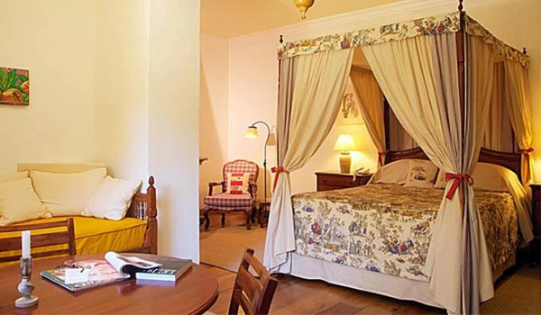 Imagem de um quarto de hotel vintage com cama de dossel, cortinas elegantes e decoração clássica, transmitindo conforto e charme para uma experiência única.