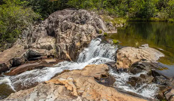 Cachoeira e rios no meio da natureza com pedras e vegetação ao redor, cenário perfeito para ecoturismo e aventuras ao ar livre. Turismo na Chapada dos Veadeiros.