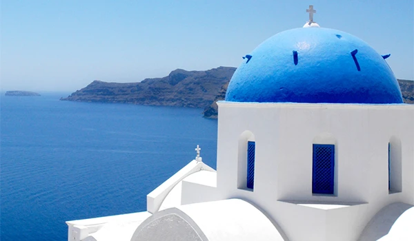 Vista da famosa igreja de Santorini com sua cúpula azul característica, vista para o mar e paisagem deslumbrante da ilha grega, ideal para fotos turísticas.