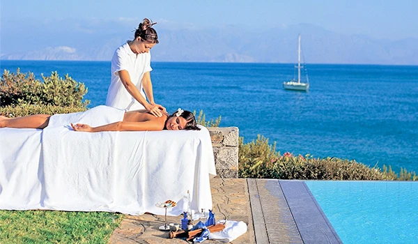 Sessão de massagem ao ar livre ao lado da piscina, com vista para o mar, promovendo relaxamento e bem-estar. Ambiente tranquilo e relaxante.