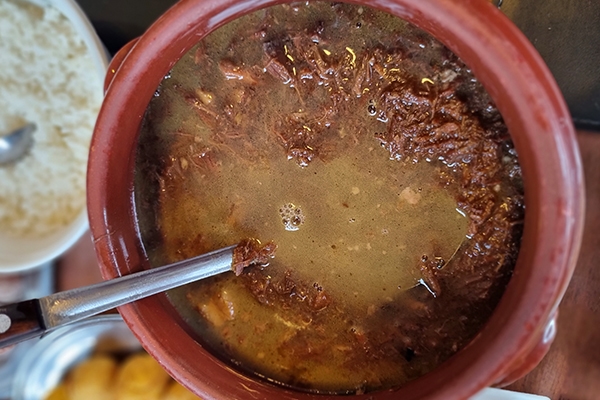 Barreado em uma panela de barro, pronto para servir, com carne e caldo saboroso e nutritivo. Onde comer em Curitiba.