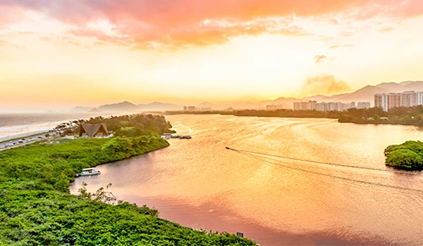 Paisagem de rio ao pôr do sol com céu colorido, rios serenos e área verde ao redor, mostrando uma vista relaxante e bela da natureza no entardecer