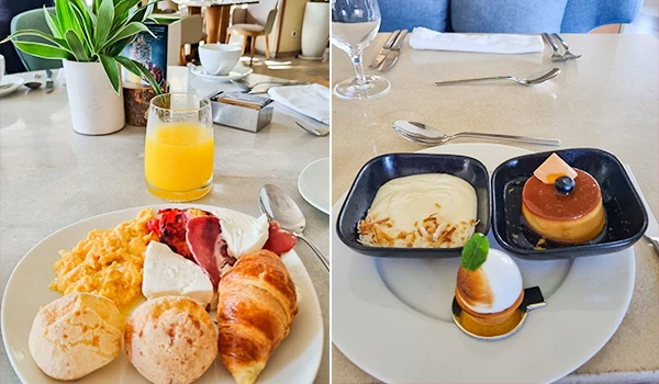 Imagem de um café da manhã completo com suco de laranja, croissants, pão, e ovos mexidos na mesa de um café ou hotel, com decoração moderna.