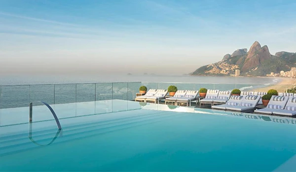 Piscina com vista para o mar e cadeiras de descanso em uma arquitetura moderna em um hotel de luxo em Rio de Janeiro.