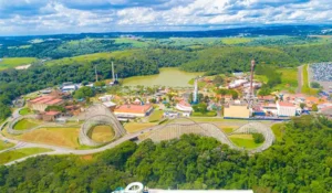 Imagem de um parque de diversidade com brinquedos de parque de diversões, árvores e uma roda gigante ao fundo, cenário perfeito para diversão e lazer. Atrações do Hopi Hari.