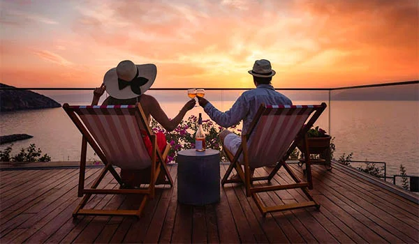 Foto de um casal em um deck observando o mar ao pôr do sol, na Lua de Mel América Latina.