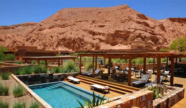 Foto de um hotel com piscina e espreguiçadeiras no Deserto do Atacama. Lua de Mel América Latina.