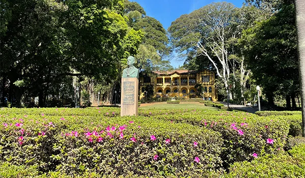 Foto da entrada do Parque da Água Branca, com casa ao fundo e estátua o centro do Jardim florido.