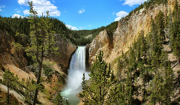 Foto do Yellowstone National Park com cachoeira no meio entre morros verdejantes.
