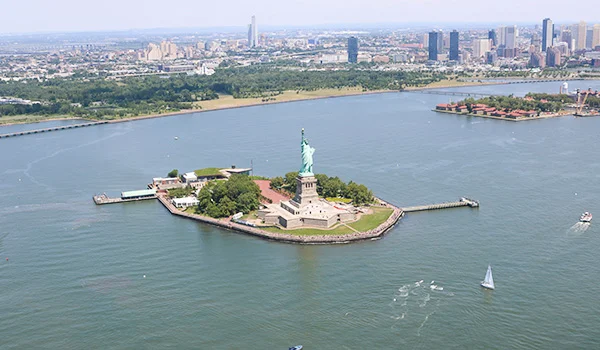 Foto aérea da pequena ilhota onde está a Estátua da Liberdade com os prédios em volta. Um dos pontos turísticos dos Estados Unidos.