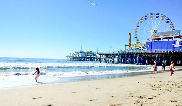 Foto do famoso Pier de Santa Monica, onde se observa a roda-gigante em com banhistas na praia.