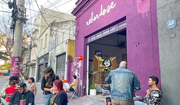 Foto da fachada do Bar Rebordose com construção pintada de roxo, e várias mesas com clientes na calçada ao ar livre.