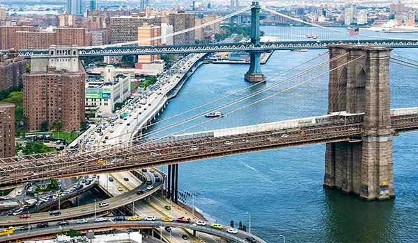 Foto aérea durante o dia da Ponte de Brooklyn com prédios em volta, em Nova York.