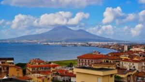 Imagem da cidade de Nápoles com construções histórica, o mar e ao fundo o Vulcao Vesúvio na Itália.