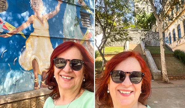 Foto em montagem com duas imagens. À esquerda, Deusa Rodrigues, usando óculos escuros e blusa verde-clara, sorri diante de um mural colorido com figuras dançando. À direita, a mesma mulher aparece sorrindo, de óculos escuros, na Escadaria do Bixiga, um local arborizado com construções antigas ao fundo.